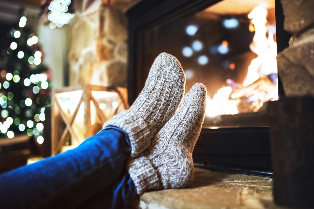 How to Keep Your House Warm This Winter Without Cranking the Heat 11 Cozy wool socks warming by the fireplace on a winter night